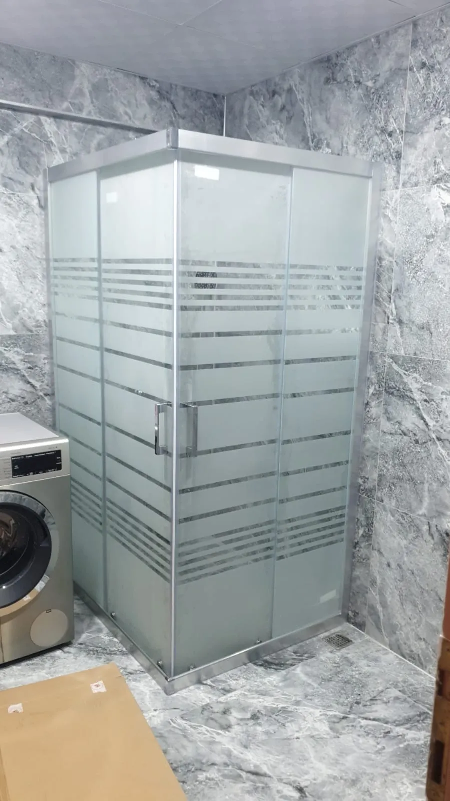 Krom profilli köşe duşakabin, yatay çizgili kumlama desenli buzlu cam, gri mermer banyo
