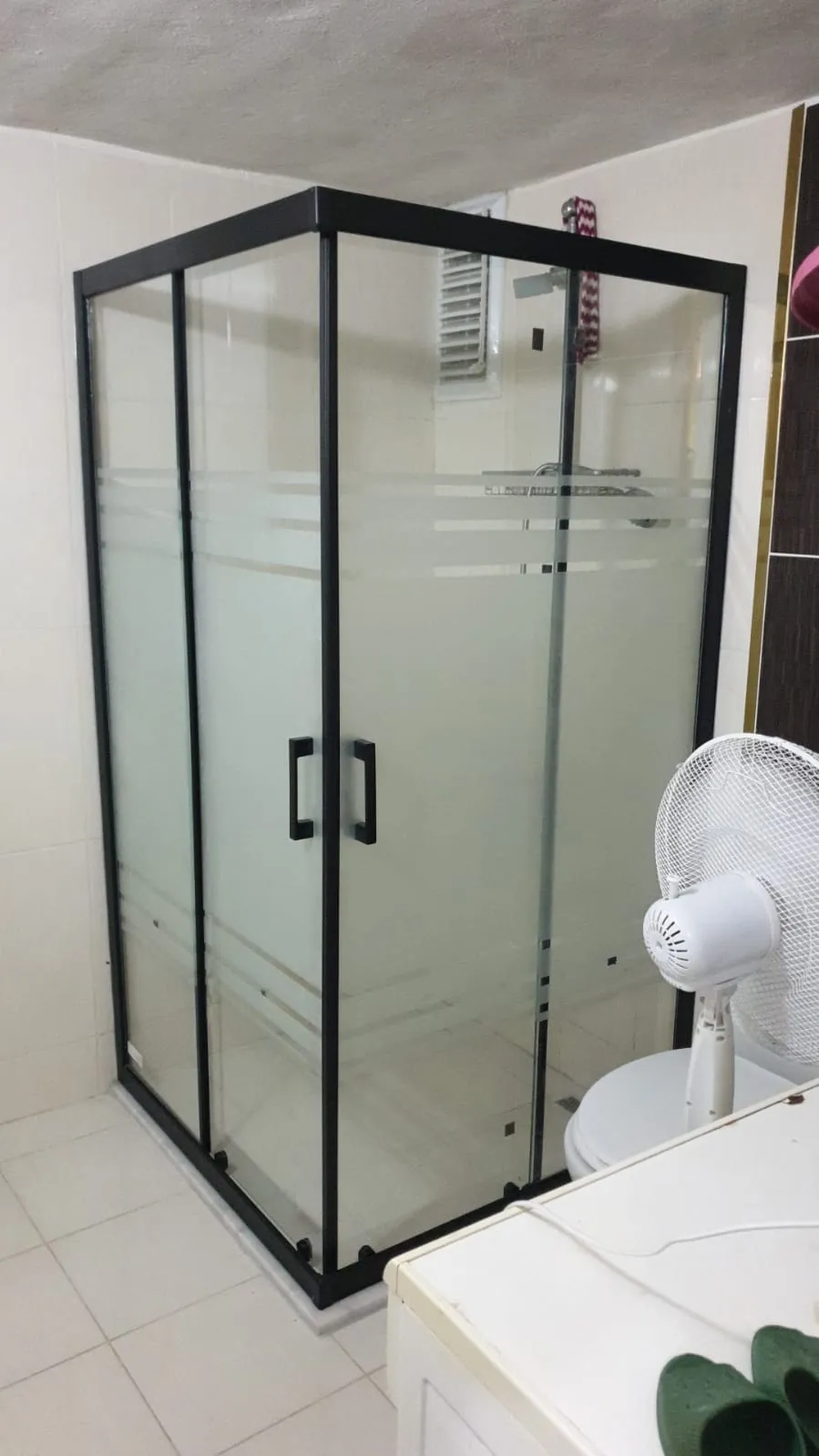 Siyah profilli köşe duşakabin, ince çizgi kumlamalı cam, açık renk banyo